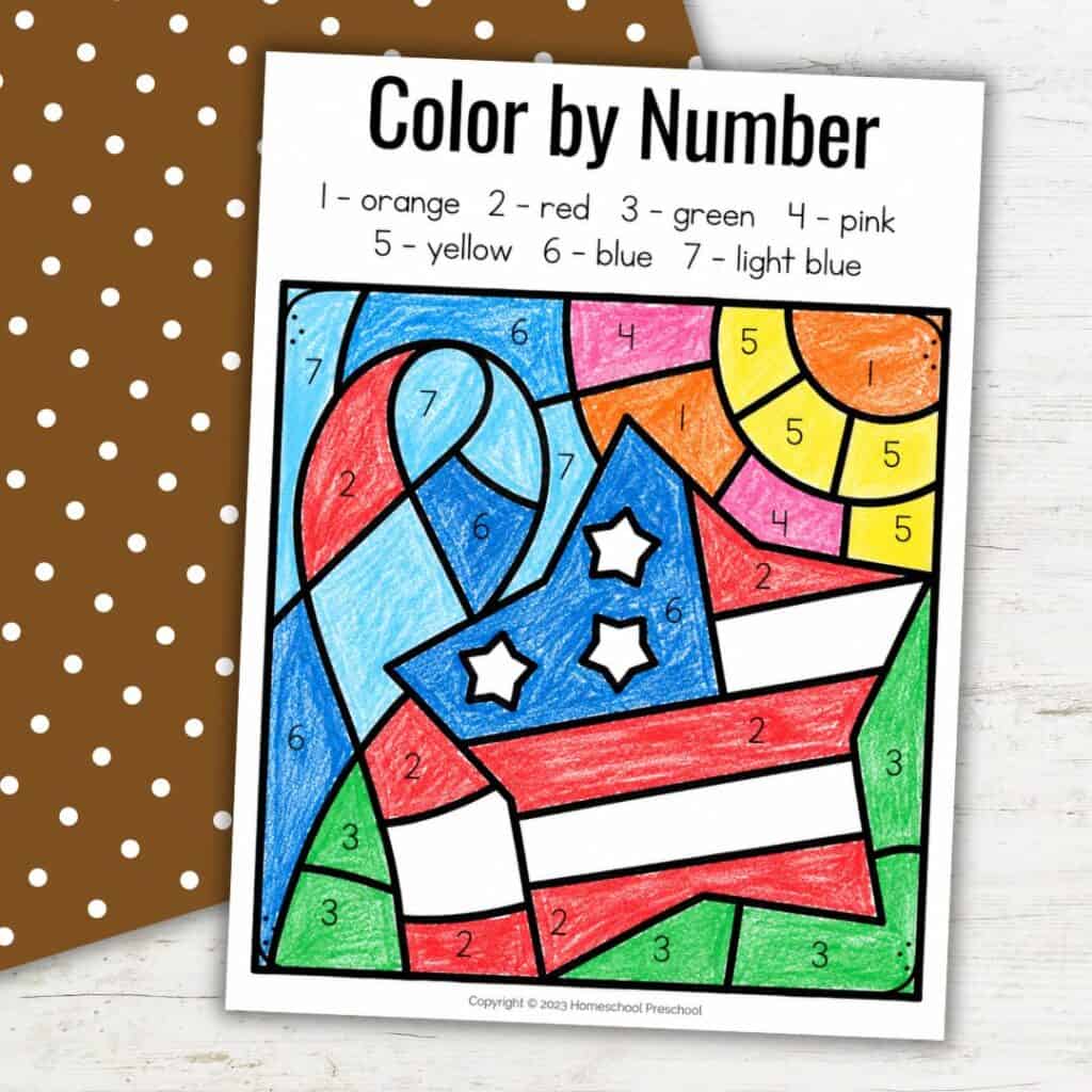 Veterans Day color by number worksheet for preschoolers, shown completed with crayons on a simple fall-themed background.