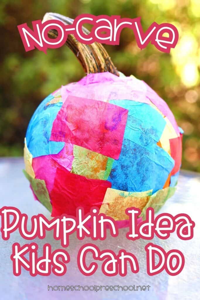 A small pumpkin covered in overlapping squares of colorful tissue paper in pink, blue, red, green, and yellow, displayed outdoors with a blurred green background.