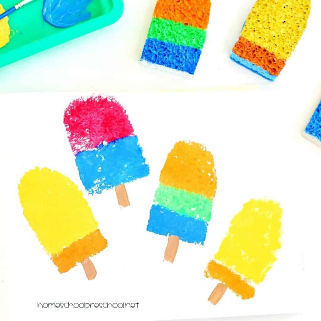 Completed sponge-painted popsicle craft with colorful stamped popsicle designs on white paper and painted sponge stamps displayed above the artwork.