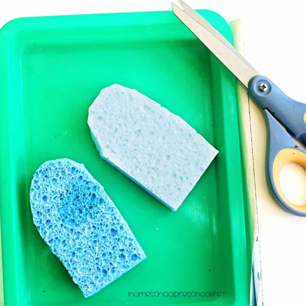 Popsicle-shaped sponges cut from household sponges and placed on a tray next to scissors for a preschool summer craft.