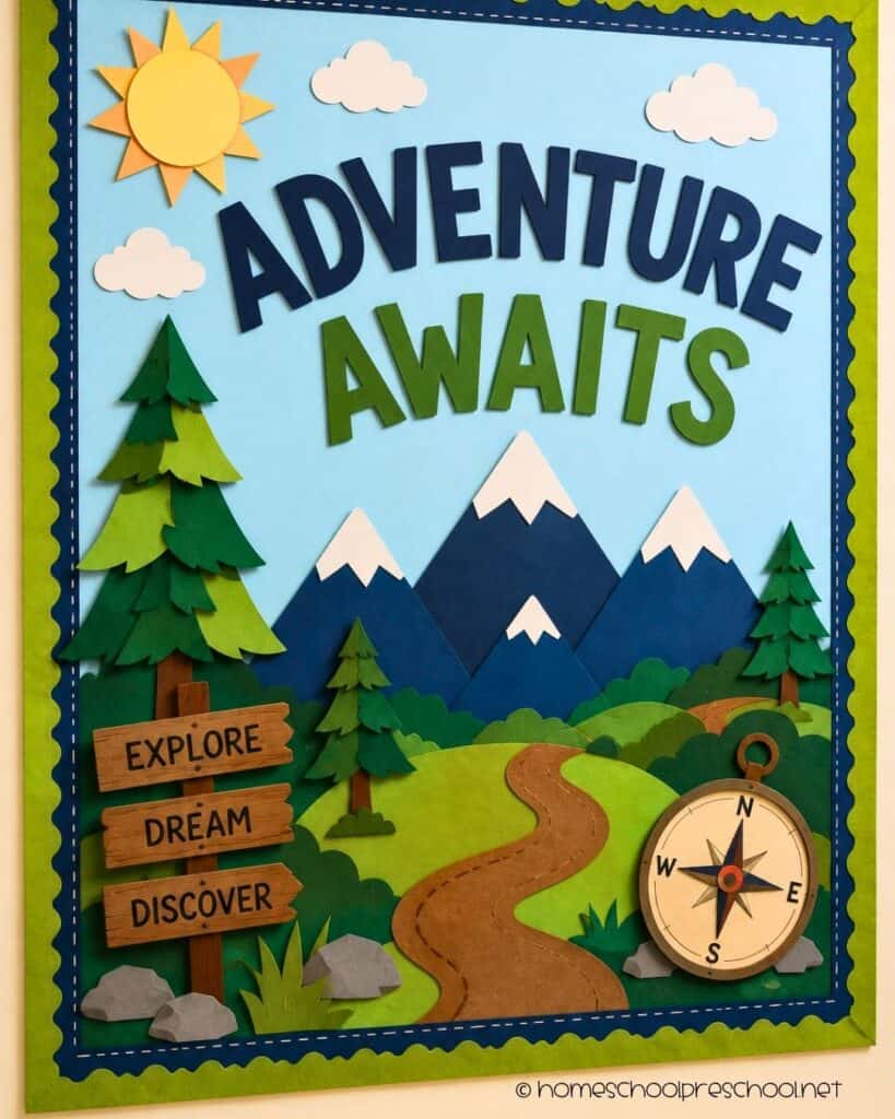 Adventure Awaits preschool bulletin board with paper mountains, pine trees, a winding trail, wooden signpost, and compass decorations.