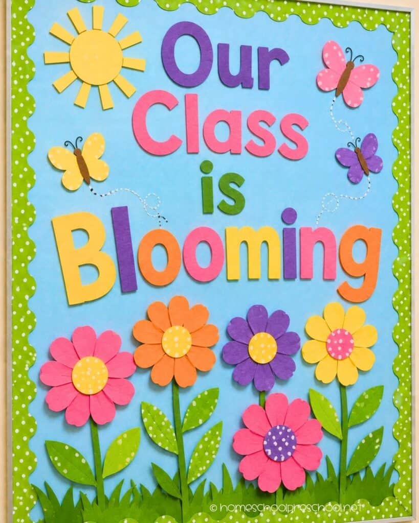 Our Class Is Blooming preschool bulletin board with colorful paper flowers, butterflies, sunshine, and the words "Our Class Is Blooming."