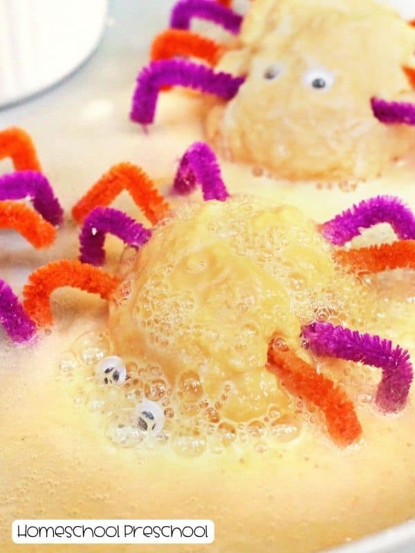 Baking soda spiders bubbling and foaming during a fizzy vinegar reaction on a tray.